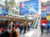 Besucher im Foyer der EuroShop in der Messe Düsseldorf mit Willkommensscreen und Themenübersicht