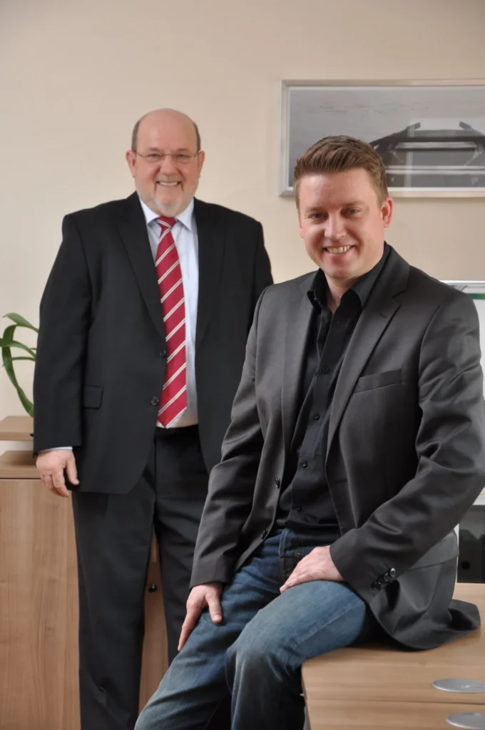 Firmengründer Adolf Telsnig und Inhaber Kai Telsnig stehen gemeinsam im Büro – Symbol für 50 Jahre Herkules Motorgeräte und Familienunternehmen.